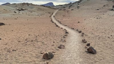 A winding path marked by rocks in the arid landscape of Teide National Park, Tenerife.